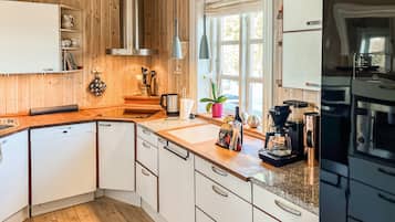 Une cuisine moderne avec des meubles en bois, un four encastré et une machine à café.