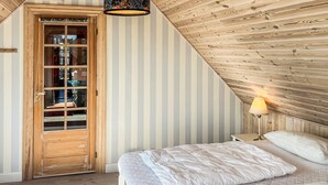 Une chambre avec un plafond en pente, une porte en bois et une lampe de chevet.
