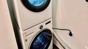 A stacked washer and dryer unit with a digital display and control panel. - Glamorous Hideaway (Gainesville)