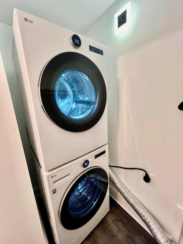 A stacked washer and dryer unit with a digital display and control panel. - Glamorous Hideaway (Gainesville)