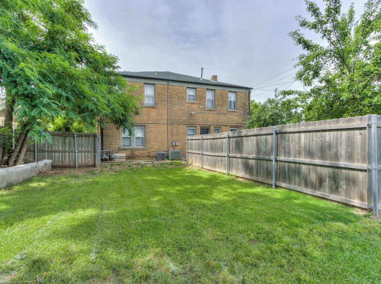 A two-story brick building with a fenced backyard.