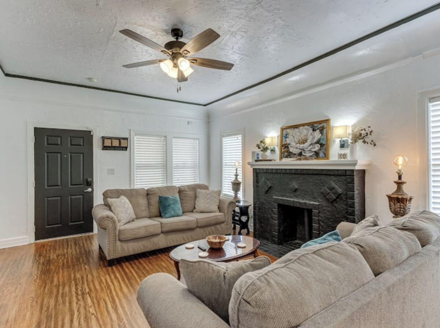 Una sala de estar con chimenea, ventilador de techo y puerta.