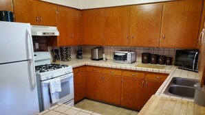 Uma cozinha com armários de madeira, fogão a gás, forno embutido, torradeira e pia.