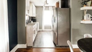 A modern kitchen with a stainless steel refrigerator, wooden flooring, and white cabinetry. - 7 min to Downtown / W/D / Historic / Central (Oklahoma City)