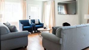 A modern living room with two sofas, a coffee table, and a TV mounted on the wall. - Perfect for Large Groups /Walkable /Plaza (Oklahoma City)