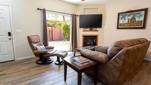 A living room with a leather sofa, a recliner, a coffee table, a fireplace, and a TV mounted on the wall. - Kanab Vacation Rental Condo, Pool, Hot Tub, Gym, 3BR 2BA Close to Zion NP! (Kanab)