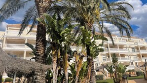 Un hôtel doté de nombreux balcons, de palmiers et d’un jardin bien entretenu.