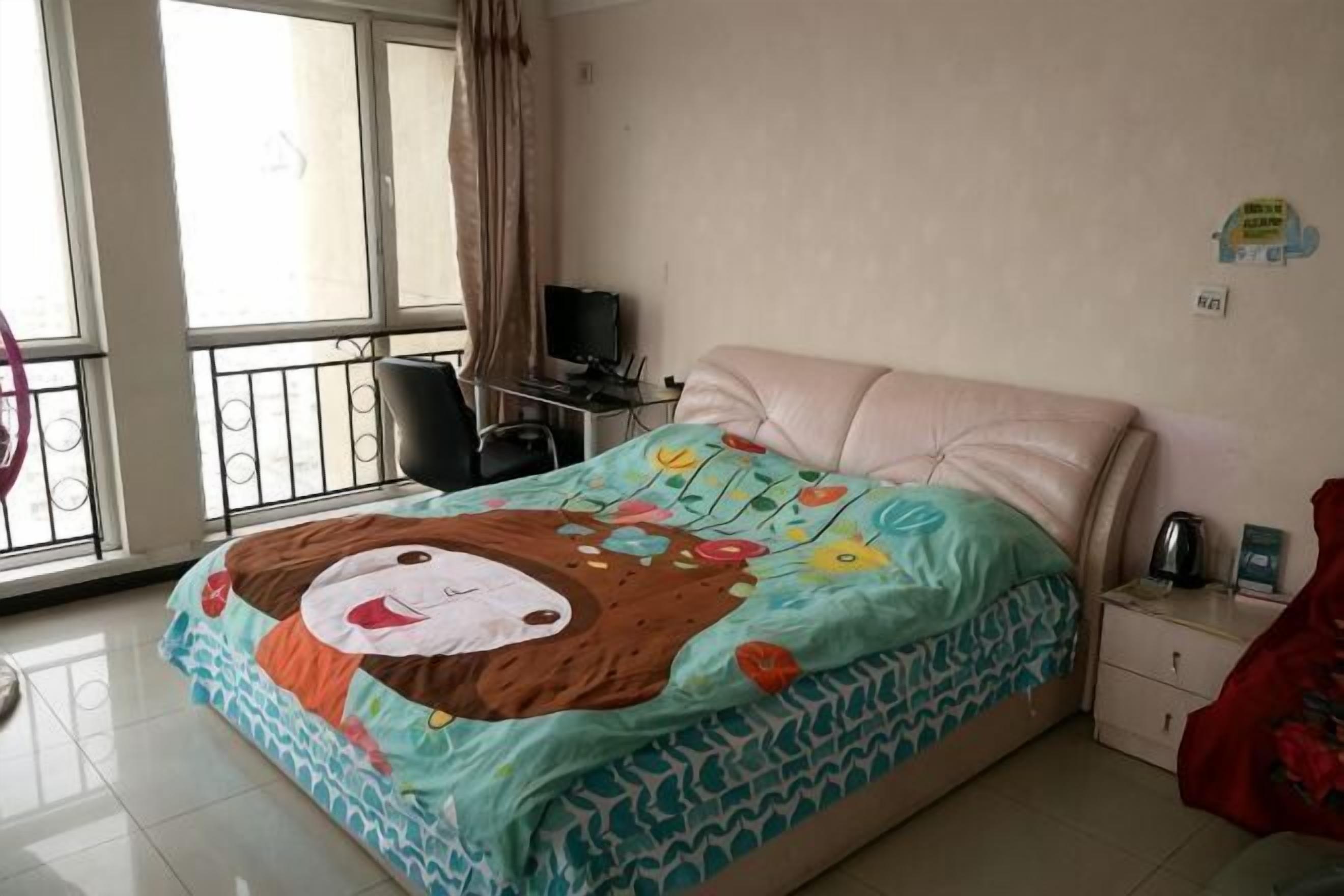 A bedroom with a bed, a desk, a chair, and a window with curtains.