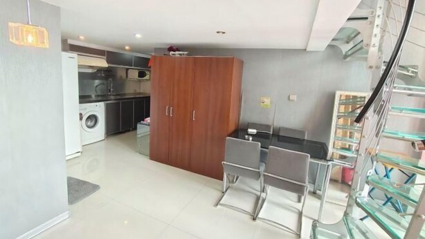 A modern kitchen with a washing machine, a wooden cabinet, and a dining area with chairs. - Shenyang Huanggu Kelaiyi Short Rent Apartment (Shenyang)
