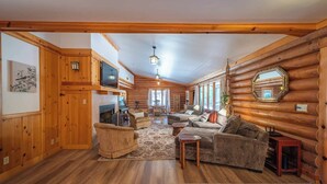 A log cabin interior with a living room, fireplace, and wooden walls.