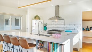Eine moderne Küche mit einer zentralen Kochinsel, Edelstahlgeräten und einer weißen Spritzschutzwand.