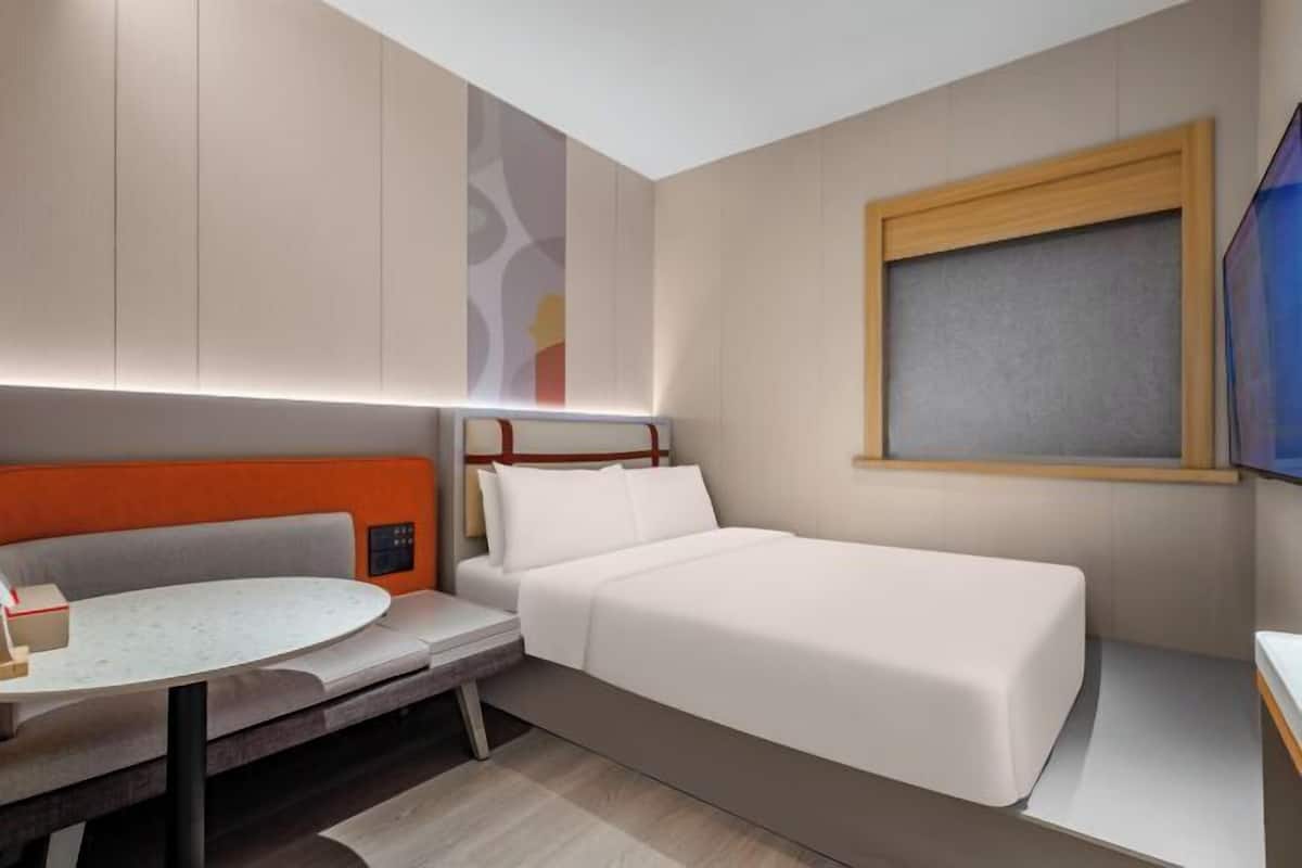 Ein Hotelzimmer mit Bett, Sitzecke mit Tisch und Fenster.