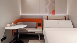 A modern hotel room with a bed, a small table, and a seating area with a control panel. - Home Inn (Shanghai Stadium Wanping South Road) (Shanghai)