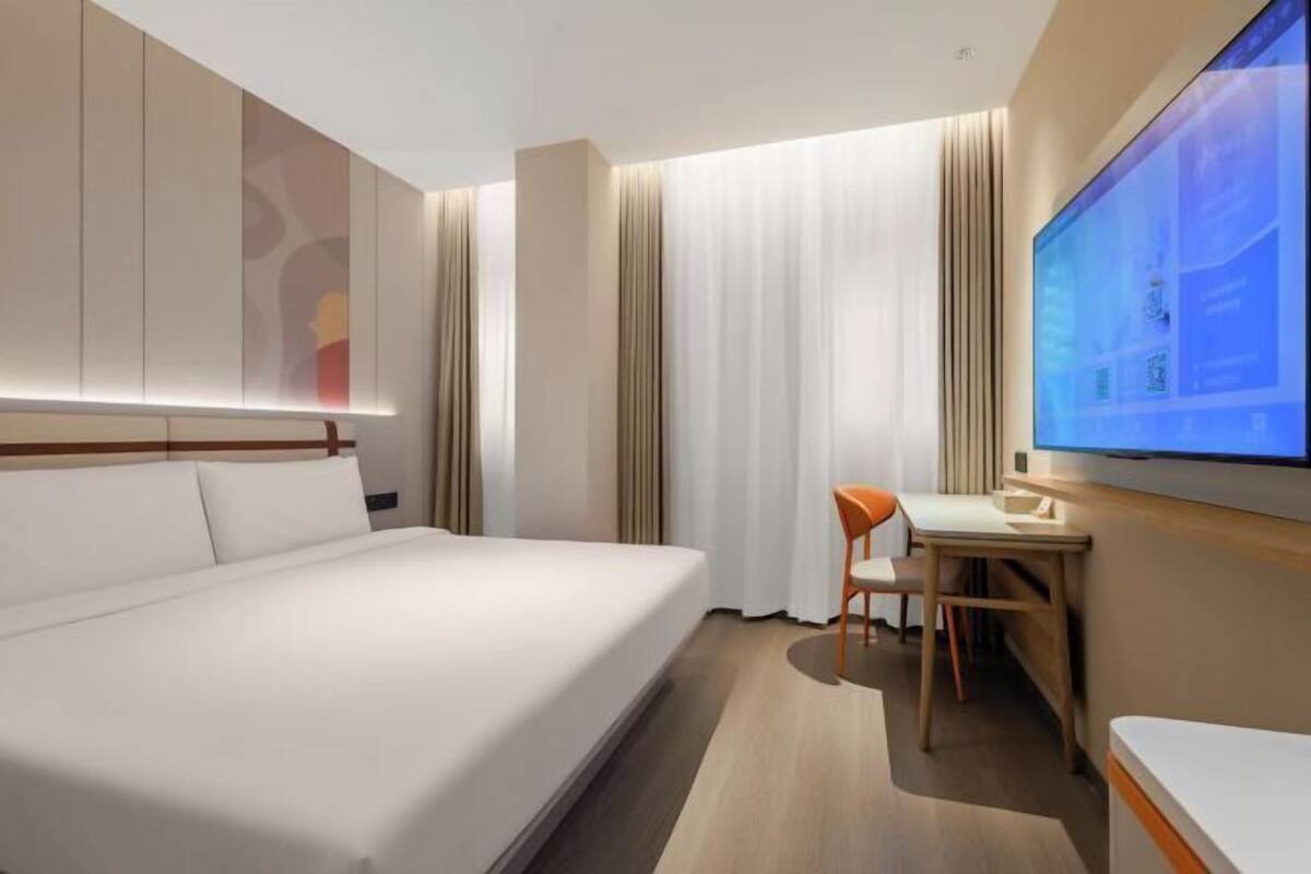 Ein modernes Hotelzimmer mit einem großen Bett, einem Schreibtisch und einem Flachbildfernseher.