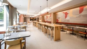 A modern restaurant with long communal tables and booths, large windows, and abstract wall art. - Home Inn (Shanghai Stadium Wanping South Road) (Shanghai)