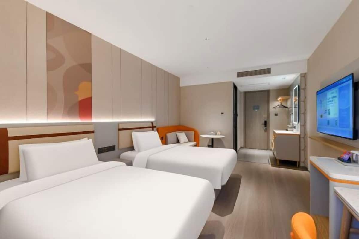 Ein Hotelzimmer mit zwei Betten, einem Schreibtisch, einem Fernseher und einem Badezimmer.