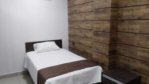 A bedroom with a bed, a nightstand, and a wooden accent wall.