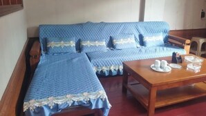 A room with a blue sofa set, a wooden coffee table with cups, and framed botanical prints on the wall. - Congjian Huadu Hotel (Congjiang)