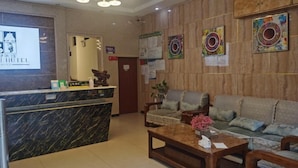 A hotel reception area with a marble counter, a sofa set, and decorative wall art. - Congjian Huadu Hotel (Congjiang)