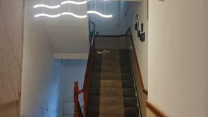 A staircase with a wooden handrail and a modern light fixture above. - Congjian Huadu Hotel (Congjiang)