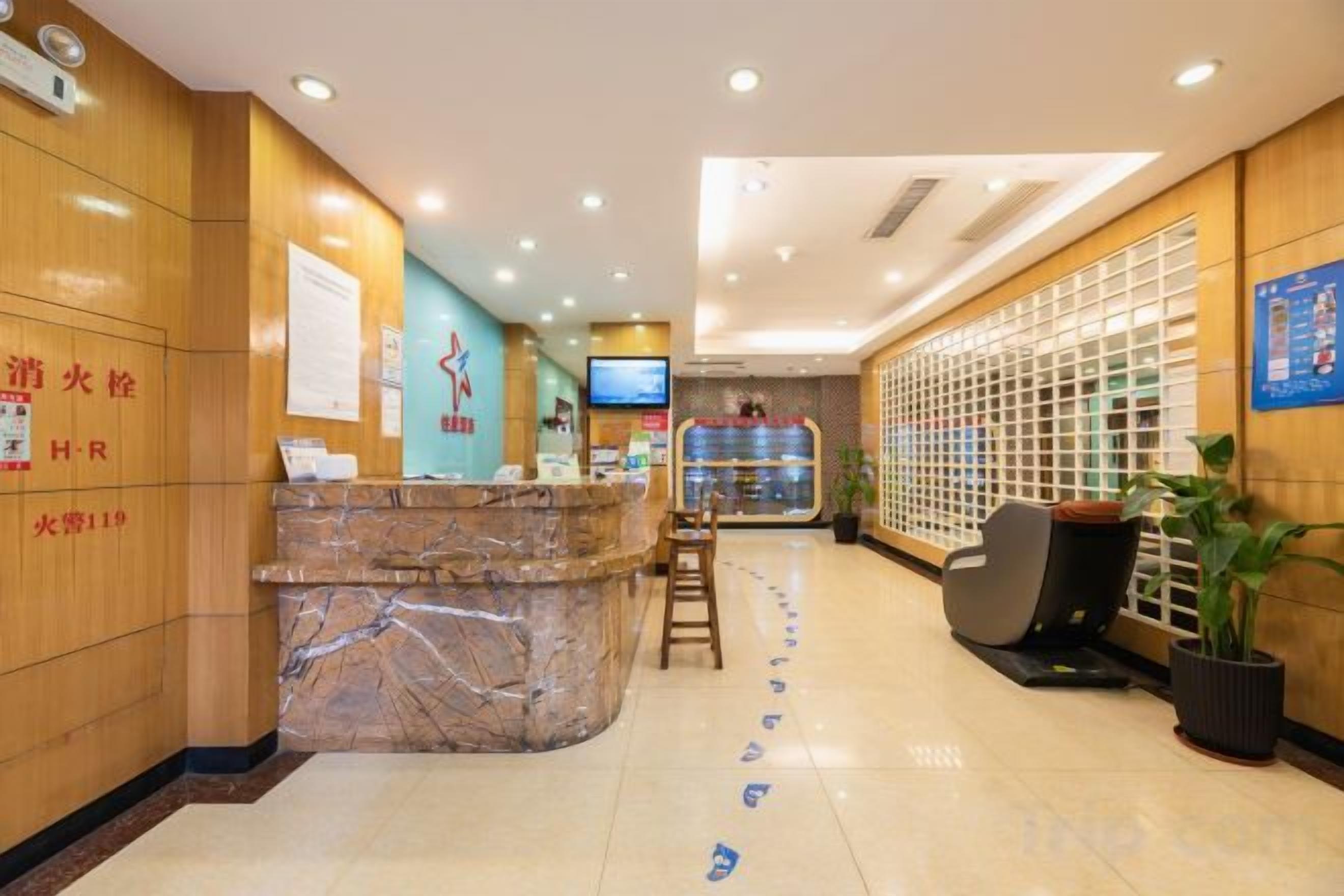 A hotel reception area with a marble counter, seating, a television, and a decorative plant.