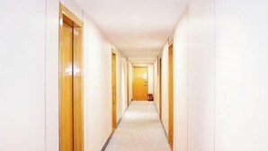 A long, narrow hallway with wooden doors on both sides and a light-colored carpet. - ZhuXing Hotel (Guangzhou)