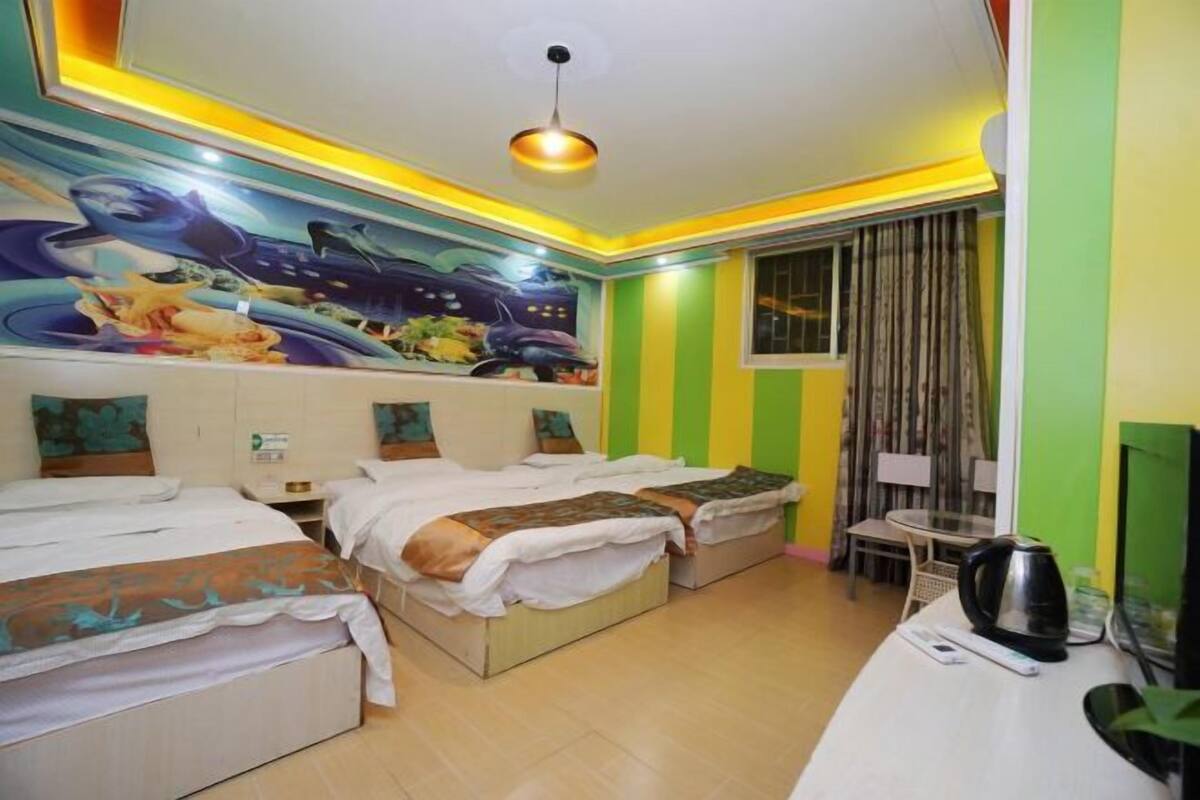 Une chambre d’hôtel avec deux lits, une petite table, une chaise, un téléviseur et une fresque murale.