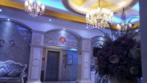Eine Lobby mit Marmorboden, einer Couch, einem Chandelier und einer großen Blumenvase.