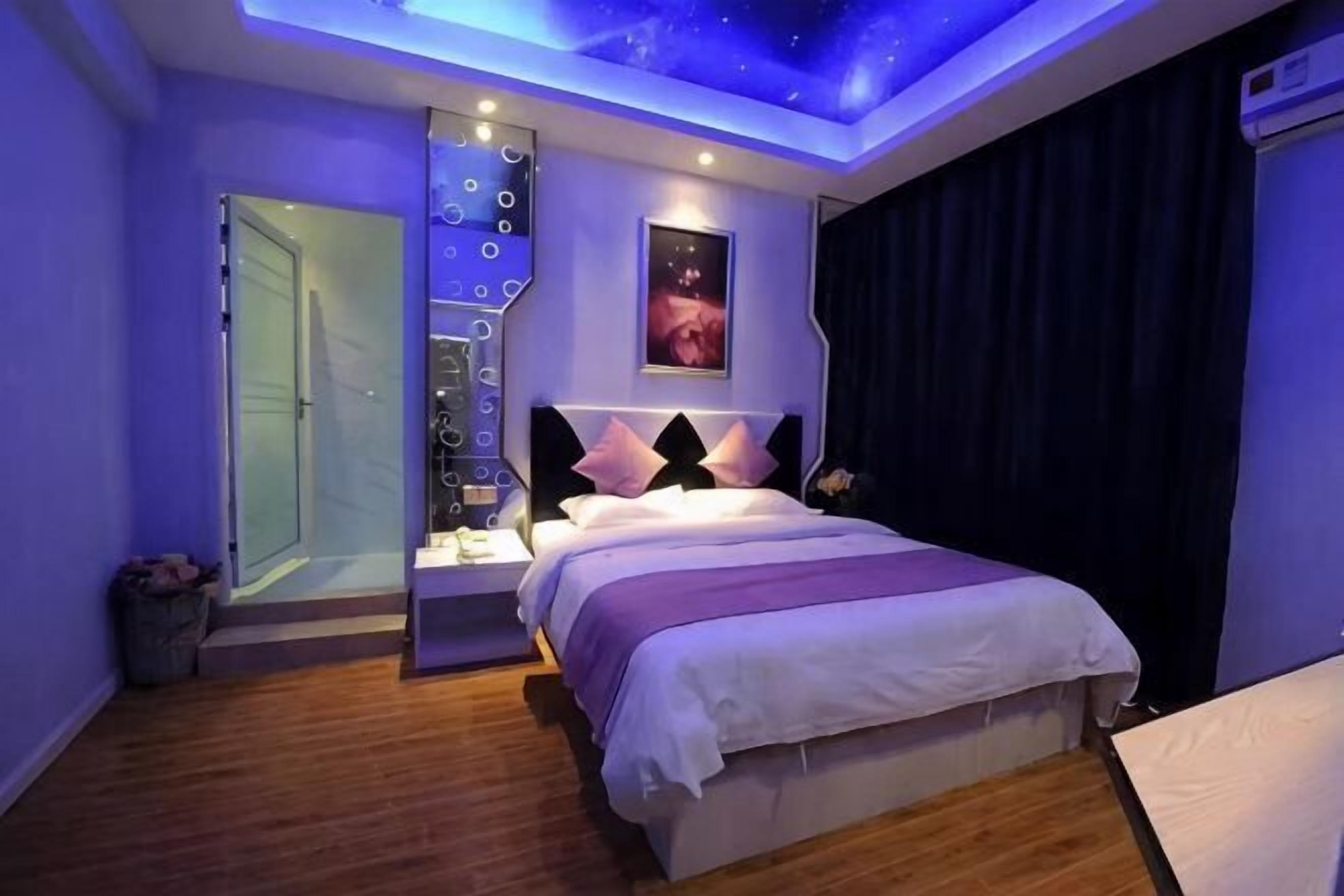 Un dormitorio con cama, mesitas de noche, lámpara de techo, ventana y puerta.