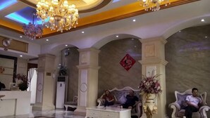 Eine Lobby mit einer Rezeption, zwei Sofas, einem Couchtisch und einem Kronleuchter.