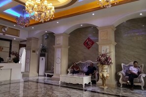 Un vestíbulo con mostrador de recepción, dos sofás, una mesa de centro y una araña.