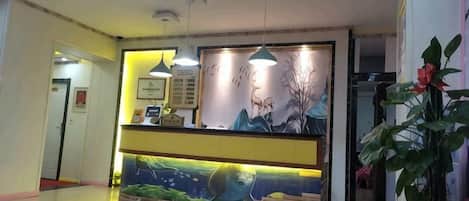 A reception area with a desk, a mural, and hanging pendant lights.