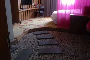 Habitación de hotel con cama, escritorio y silla. El piso está alfombrado y hay una ventana con cortinas.