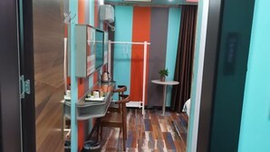 Ein kompakter Raum mit Holzboden, einem kleinen Tisch mit Stuhl, einer Wandablage und einem Blumentopf.