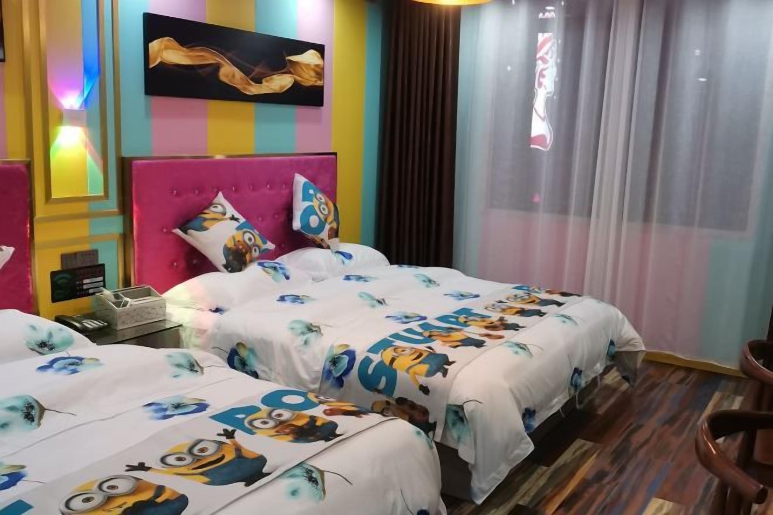 A hotel room with two beds, each with a colorful headboard and a Minion-themed bedspread.