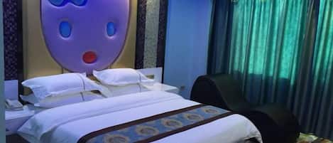 A hotel room with a large bed, a headboard with a cartoon character, a black chair, and a curtain.