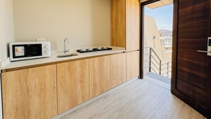 A modern kitchen with a microwave, sink, and wooden cabinets. - Casa Foresta (Salta)