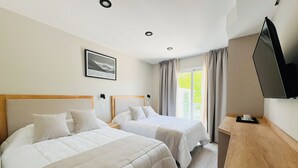 A hotel room with two beds, a wooden nightstand, a television, and a window with curtains. - Casa Foresta (Salta)