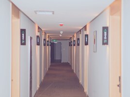 Un pasillo de hotel con puertas a ambos lados, cada una identificada con un letrero.
