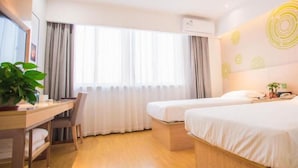 A hotel room with a desk, two beds, a TV, and a large window with curtains.