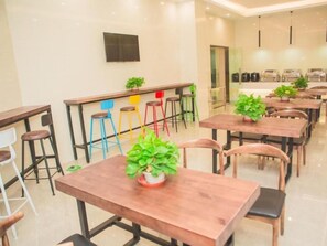 A modern dining area with multiple wooden tables and chairs, some with potted plants. - Greentree Inn Yangzhou Jiangdu Xiaoji Town South Zhongxing Road Express Hotel (Yangzhou)