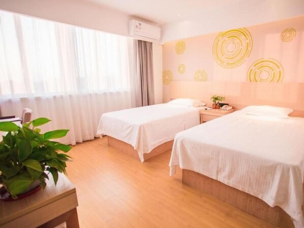 A hotel room with two beds, a bedside table, a plant, and a window with curtains. - Greentree Inn Yangzhou Jiangdu Xiaoji Town South Zhongxing Road Express Hotel (Yangzhou)