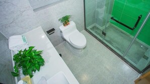 A bathroom with a white toilet, a sink with a plant, and a shower area with green tiles. - Greentree Inn Yangzhou Jiangdu Xiaoji Town South Zhongxing Road Express Hotel (Yangzhou)