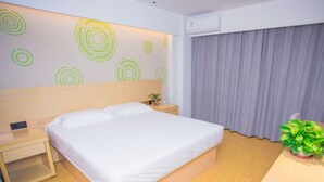 A hotel room with a bed, bedside table, nightstand, and a potted plant. - Greentree Inn Yangzhou Jiangdu Xiaoji Town South Zhongxing Road Express Hotel (Yangzhou)