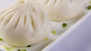 A white plate with three white, round dumplings with pleated tops, garnished with green herbs. - Greentree Inn Yangzhou Jiangdu Xiaoji Town South Zhongxing Road Express Hotel (Yangzhou)