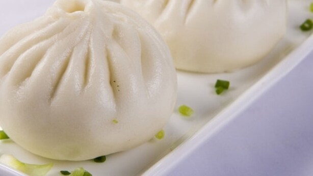 A white plate with three white, round dumplings with pleated tops, garnished with green herbs. - Greentree Inn Yangzhou Jiangdu Xiaoji Town South Zhongxing Road Express Hotel (Yangzhou)