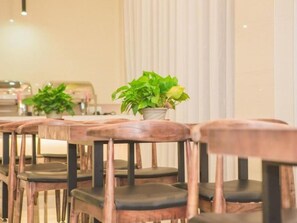 A row of wooden chairs with cushioned seats and a potted plant on a table. - Greentree Inn Yangzhou Jiangdu Xiaoji Town South Zhongxing Road Express Hotel (Yangzhou)