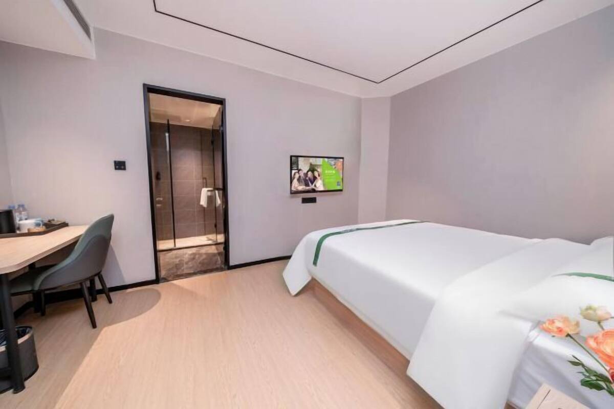 Ein Hotelzimmer mit Bett, Schreibtisch, Stuhl, Fernseher und Tür.
