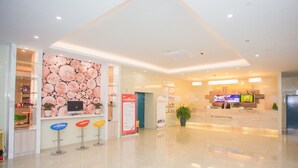 A modern hotel lobby with a reception desk, a large floral wall, and a digital screen displaying information. - Greentree Inn Yangzhou Jiangdu Xiaoji Town South Zhongxing Road Express Hotel (Yangzhou)