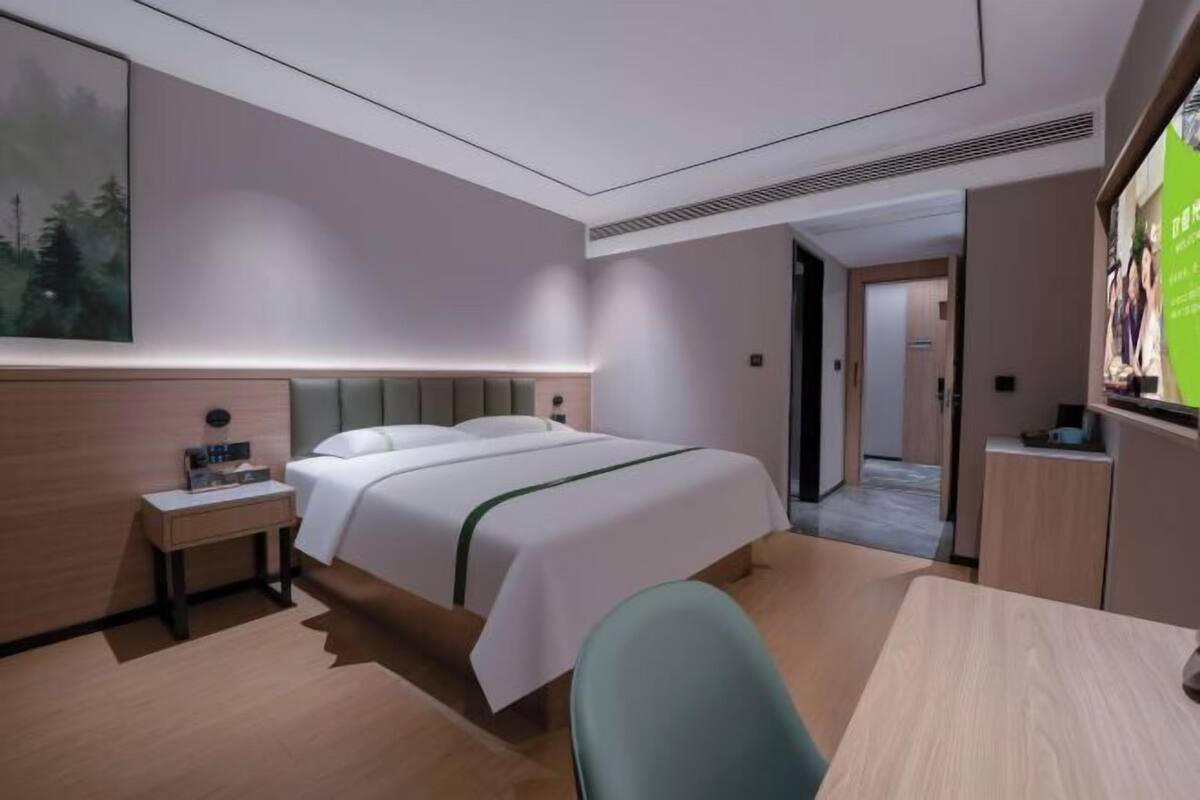 Ein Hotelzimmer mit Bett, Nachttisch, Stuhl und Schreibtisch.